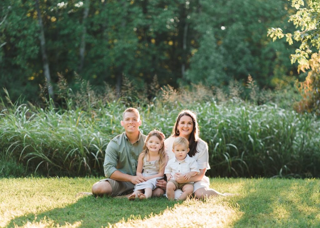 Family of four sitting in sunlight in the grass in summer session | Family Photographers Montgomery Alabama | Melissa Sheridan Photography
