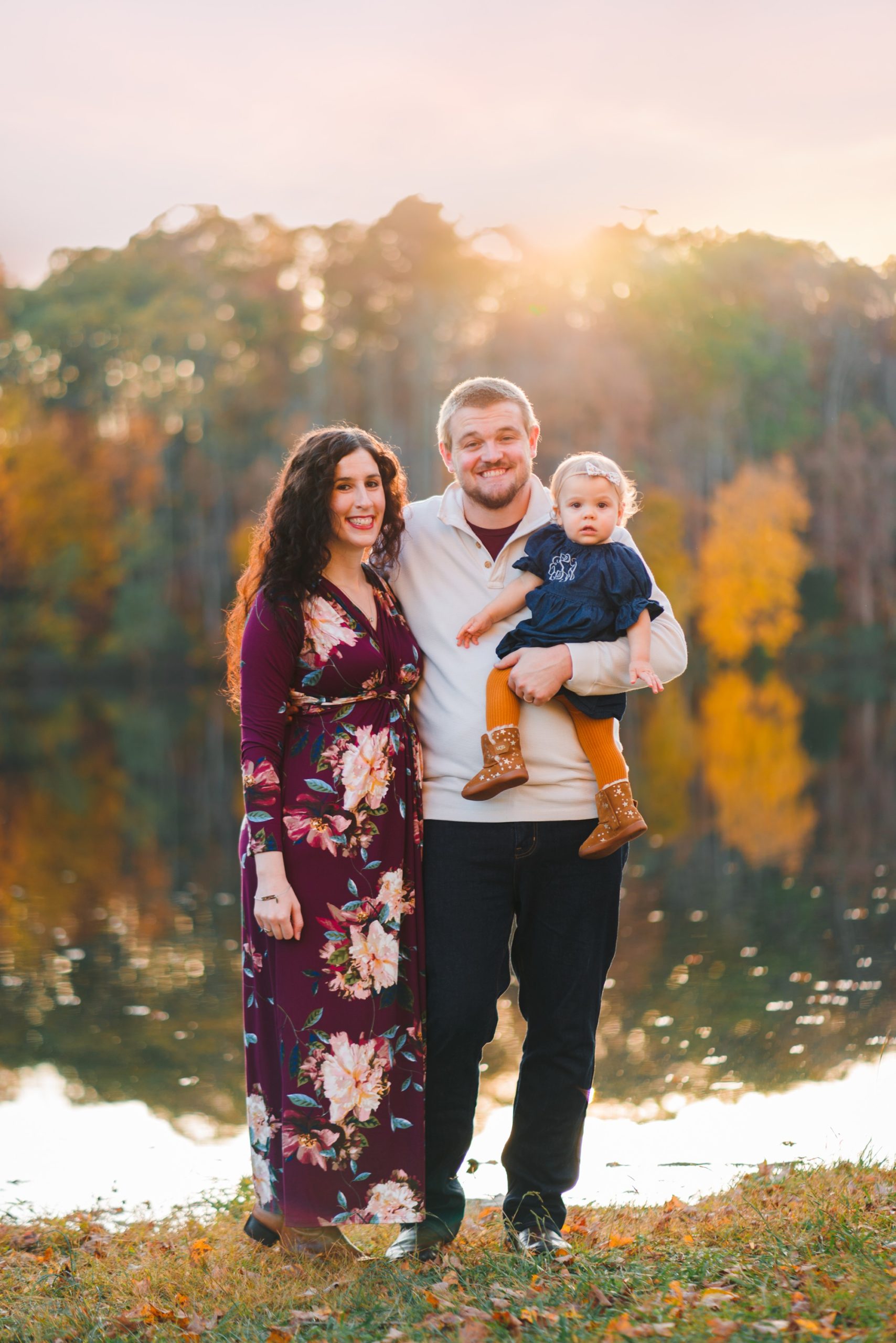 couple with baby standing in front of trees and pond | Photographers in Charlottesville
