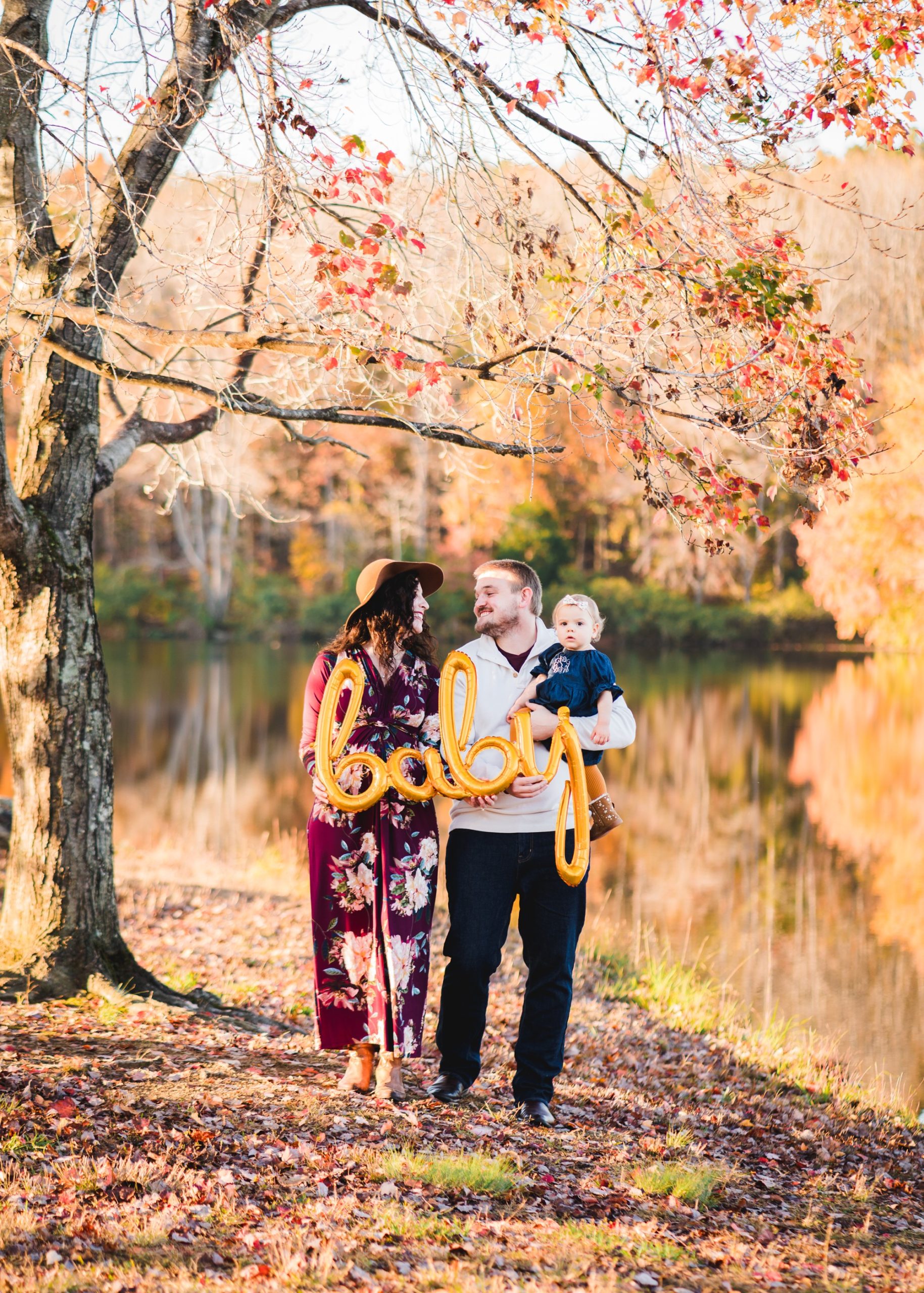 couple holding balloon that says baby in fall setting | Photographers in Charlottesville