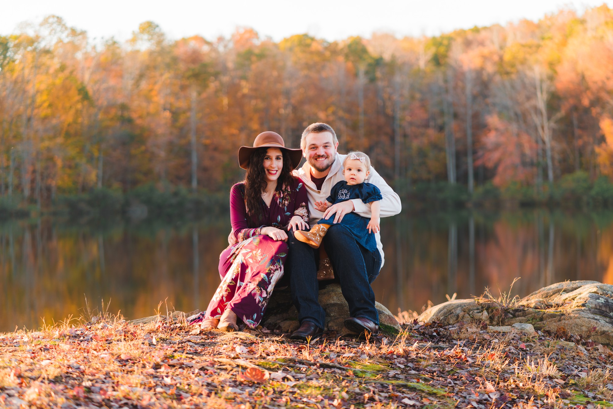 family of three sitting on a rock in front of pond | Photographers in Charlottesville
