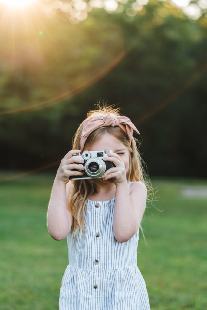 Little girl holding film camera to her face | family Photographer