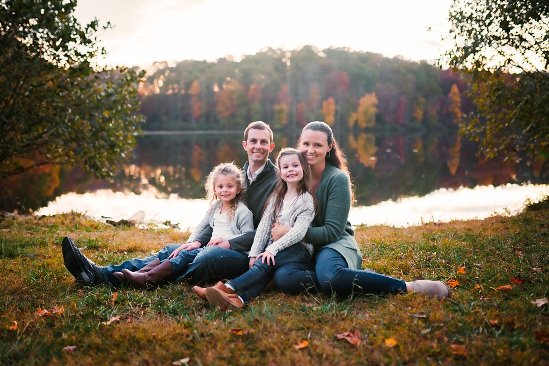 family of 4 sitting in grass in front of lake | What To Wear for Family Photos 