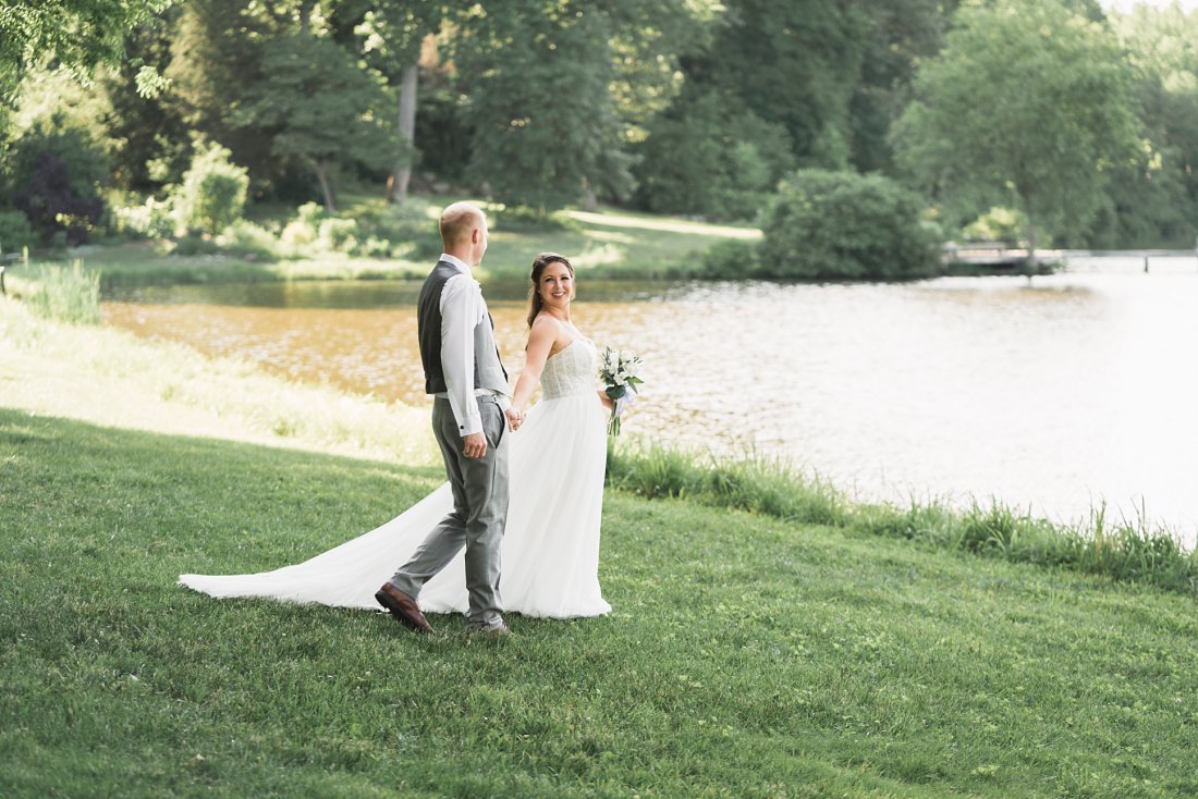Bride leading groom next to pond | Running Mare Farm Wedding