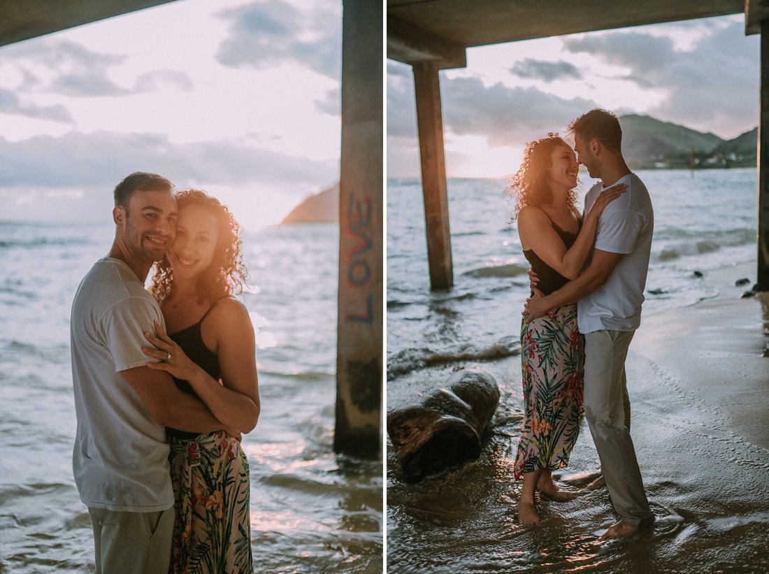 man and woman at beach under a dock | beach engagement photos