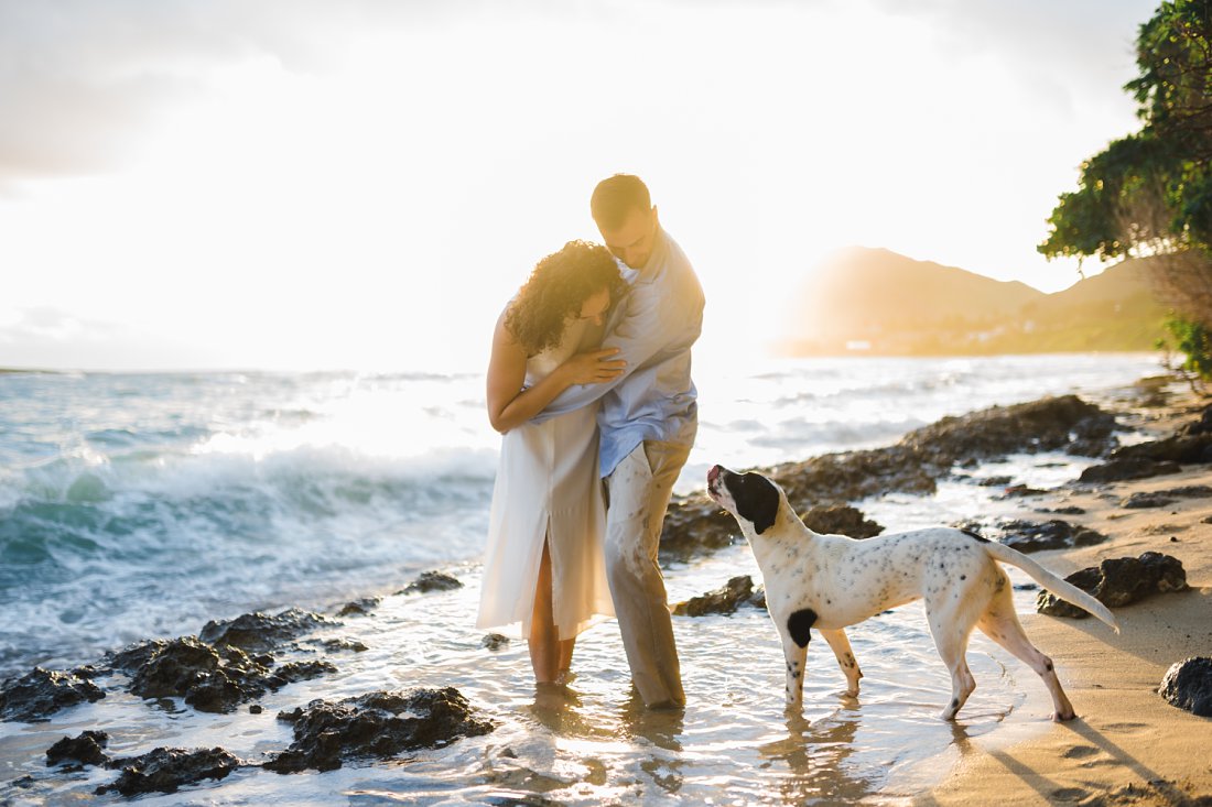 couple looking down at dog on beach | beach engagement photos