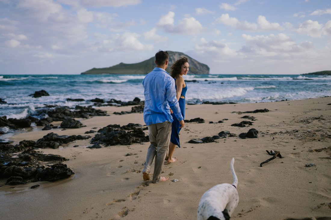 woman leading man on beach with dog | beach engagement photos