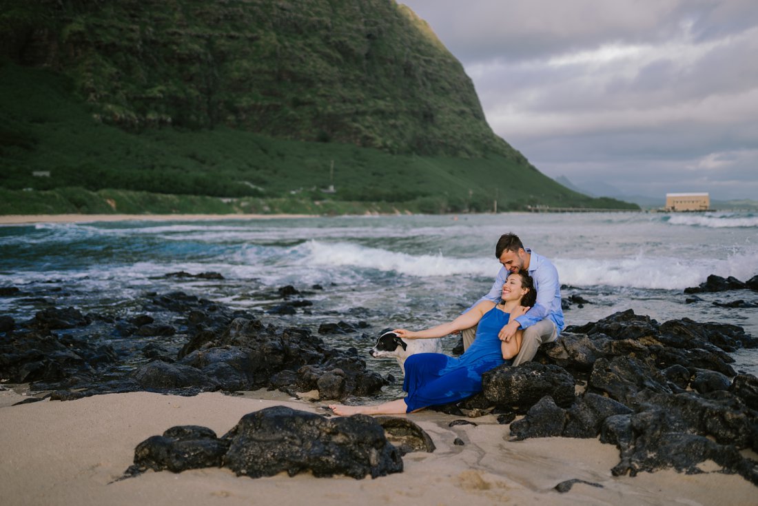couple laying on rocks at beach with dog | beach engagement photos