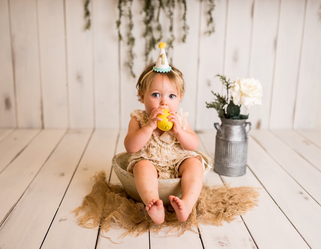 Baby girl sitting in bowl with a lemon in her mouth | Dayton First Birthday Photographer