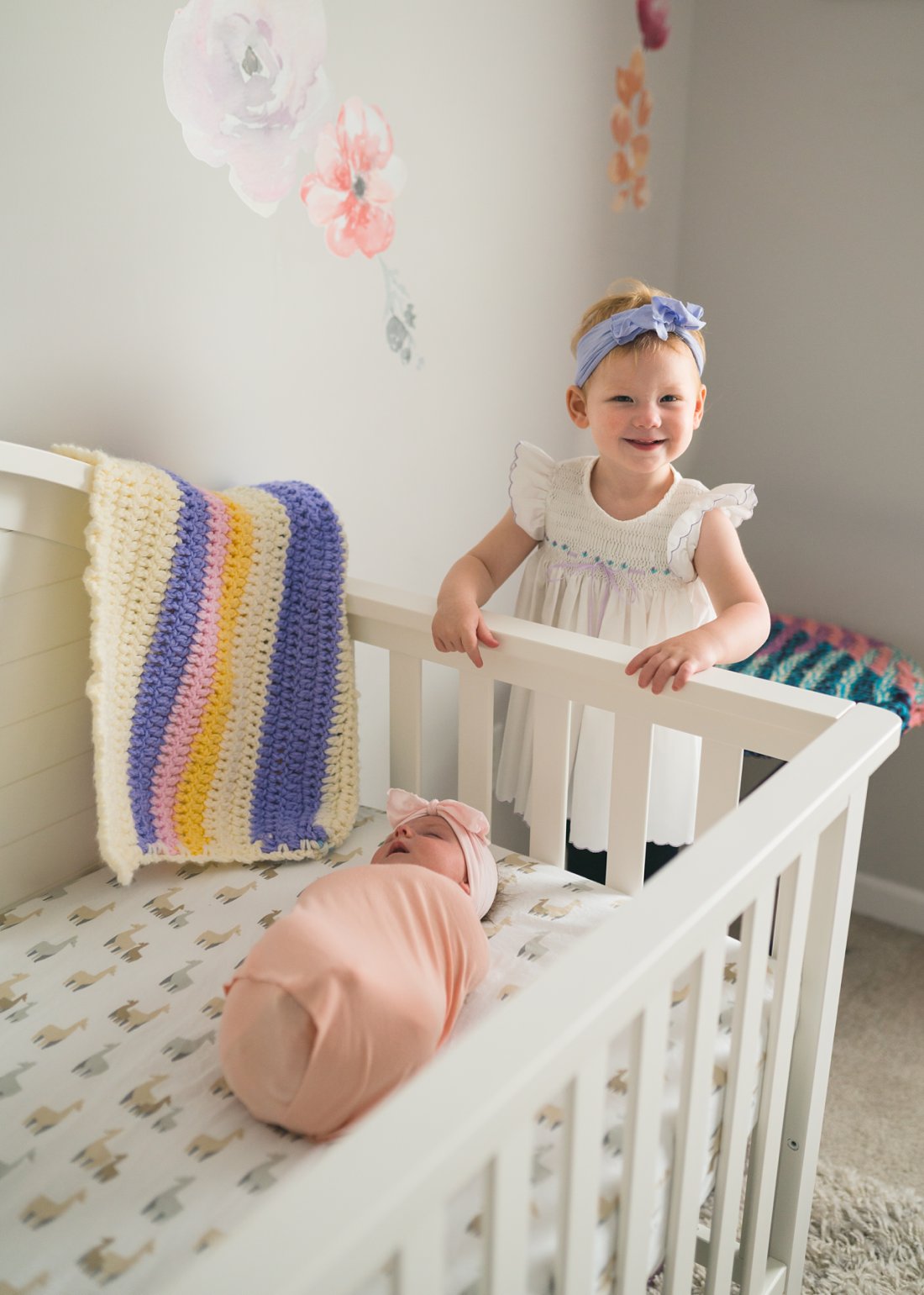 toddler next to crib with new baby in it
