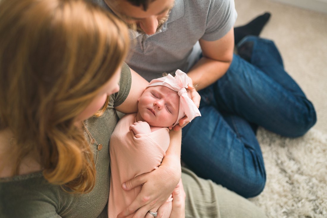 mom and dad holding new baby girl in pink | Dayton Newborn Lifestyle Photographer