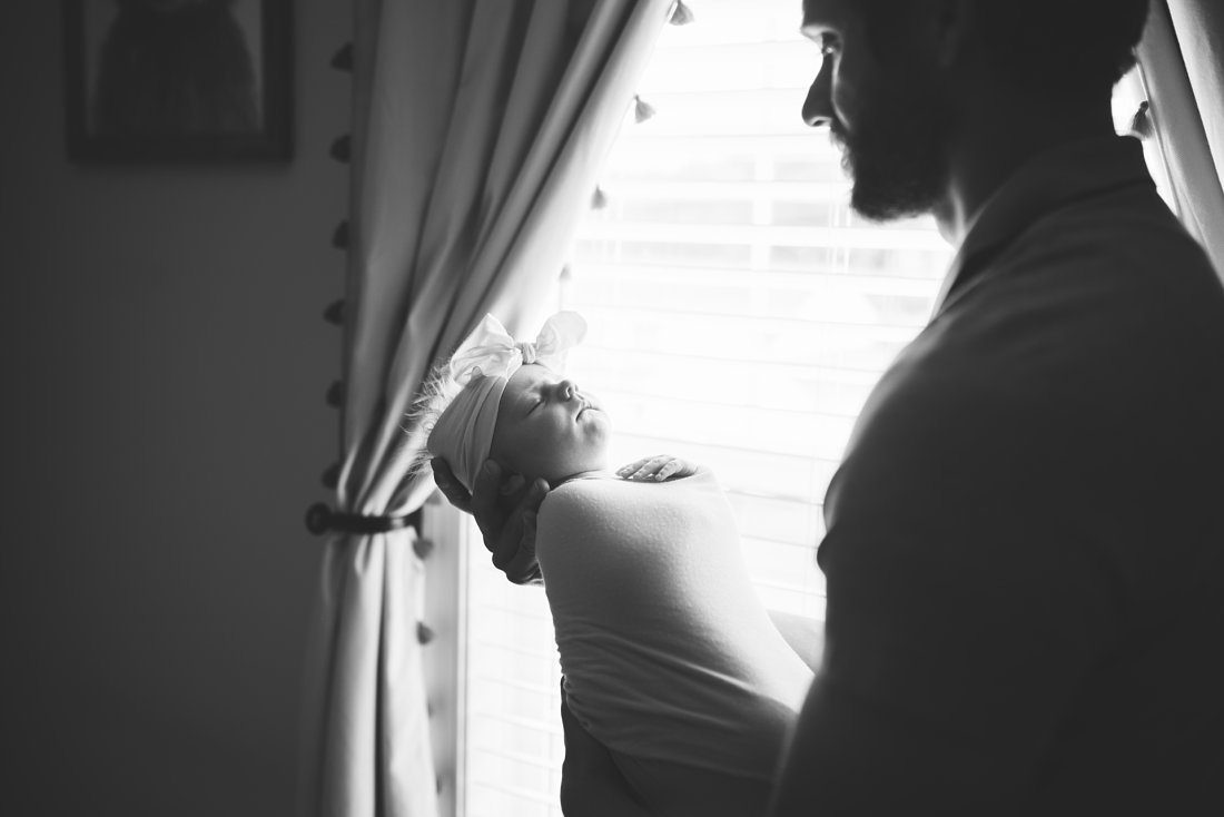 dad holding baby girl in front of window