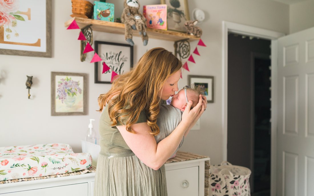 mom kissing baby girl in nursery | Montgomery Alabama newborn lifestyle photographer
