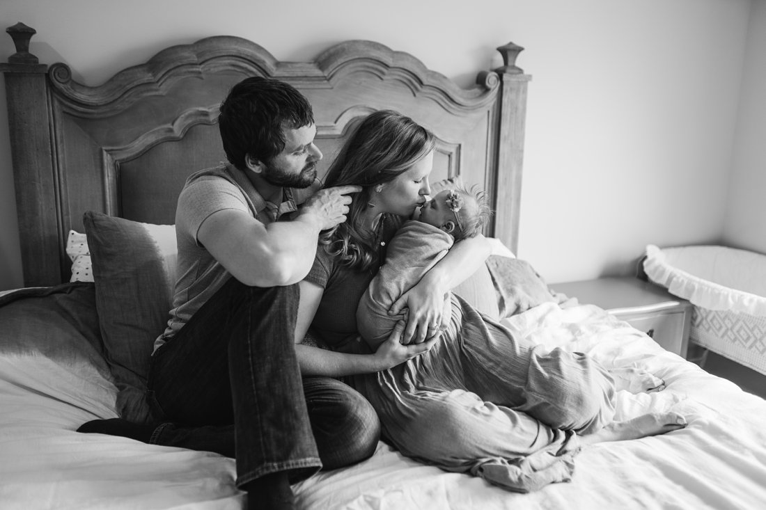 dad holding back moms hair as she kisses newborn baby | Montgomery Alabama newborn lifestyle photographer