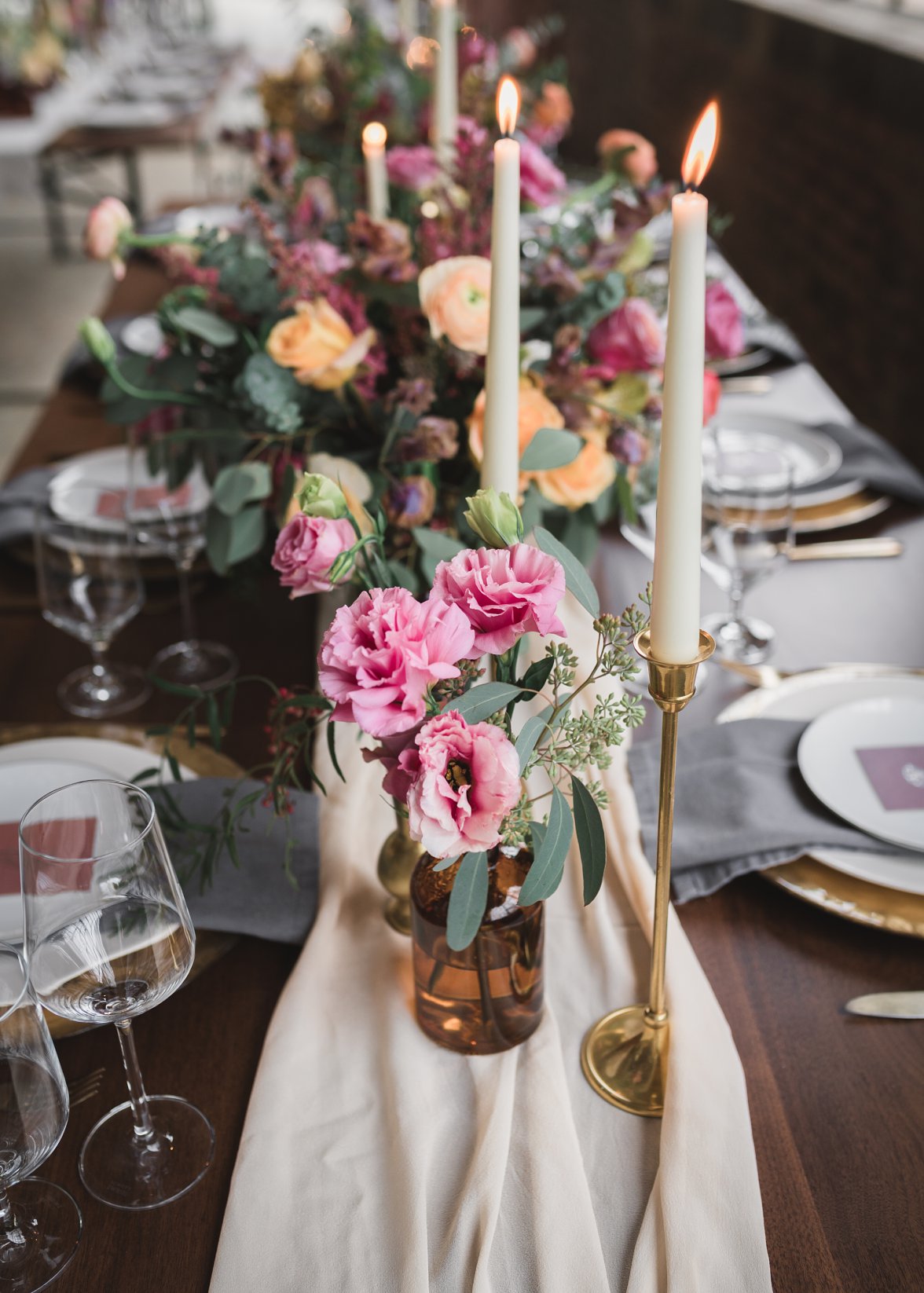 lit taper candles and flowers on a set table