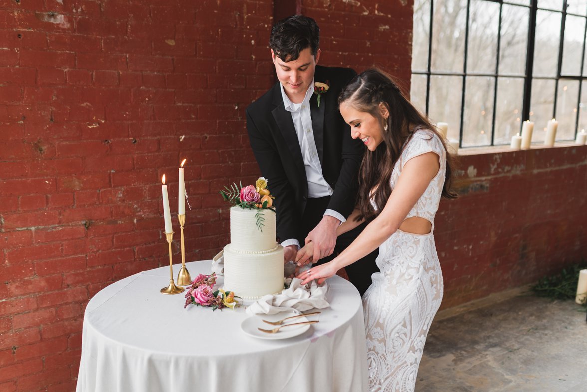 bride and groom cutting cake in front of red wall | Charlottesville Wedding Photographer