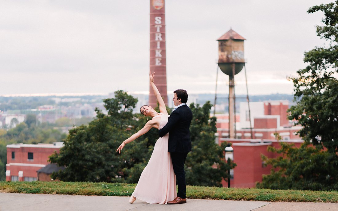 woman in ballet pose with man in front of Richmond skyline | libby hill engagement session