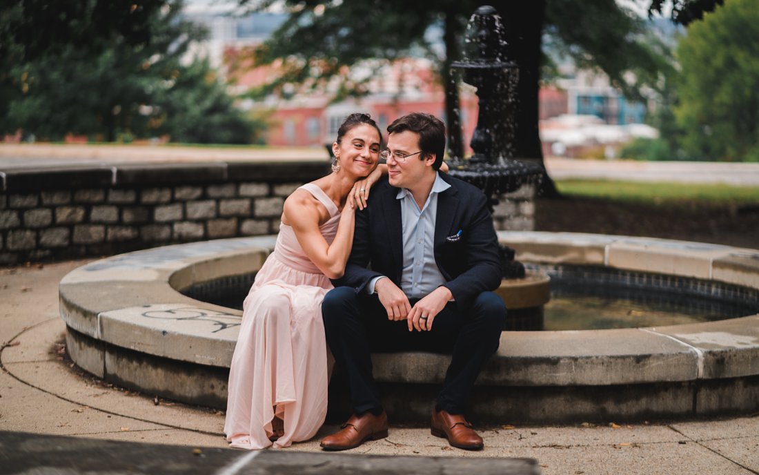 woman leaning on man's shoulder in front of fountain | libby hill engagement session