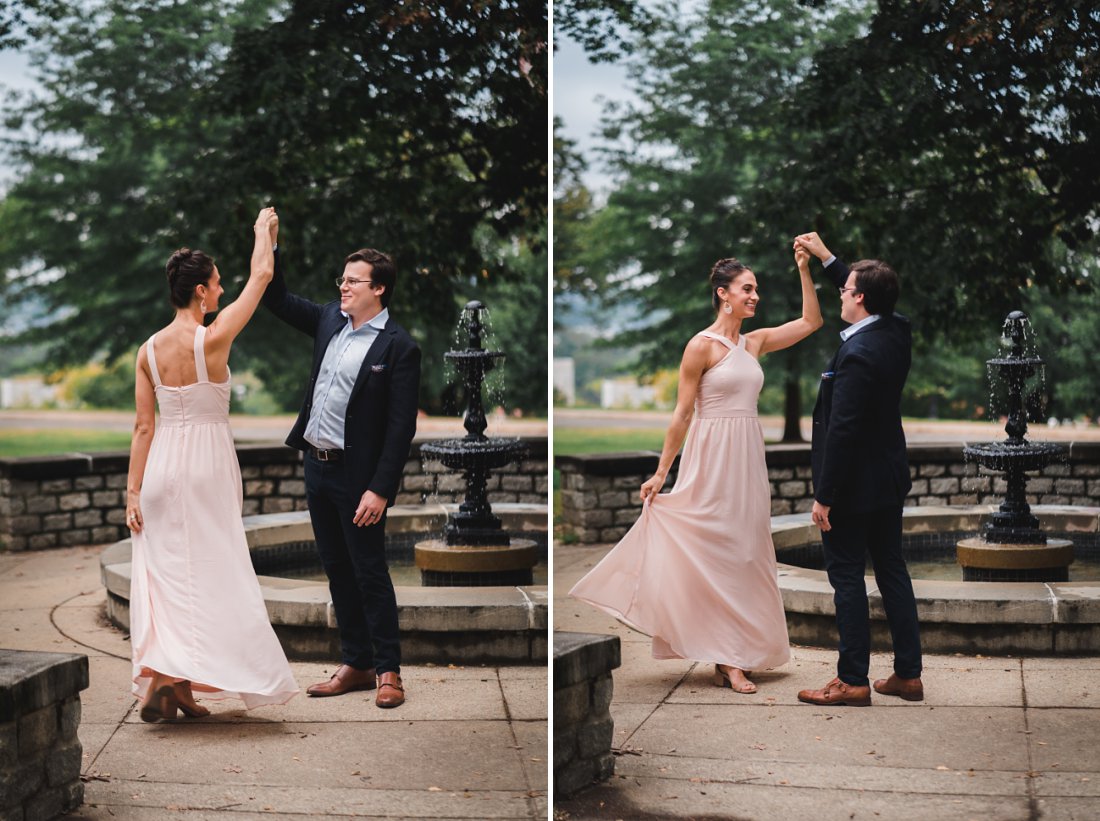 woman in pink dress being twirled by man in front of fountain | libby hill engagement session