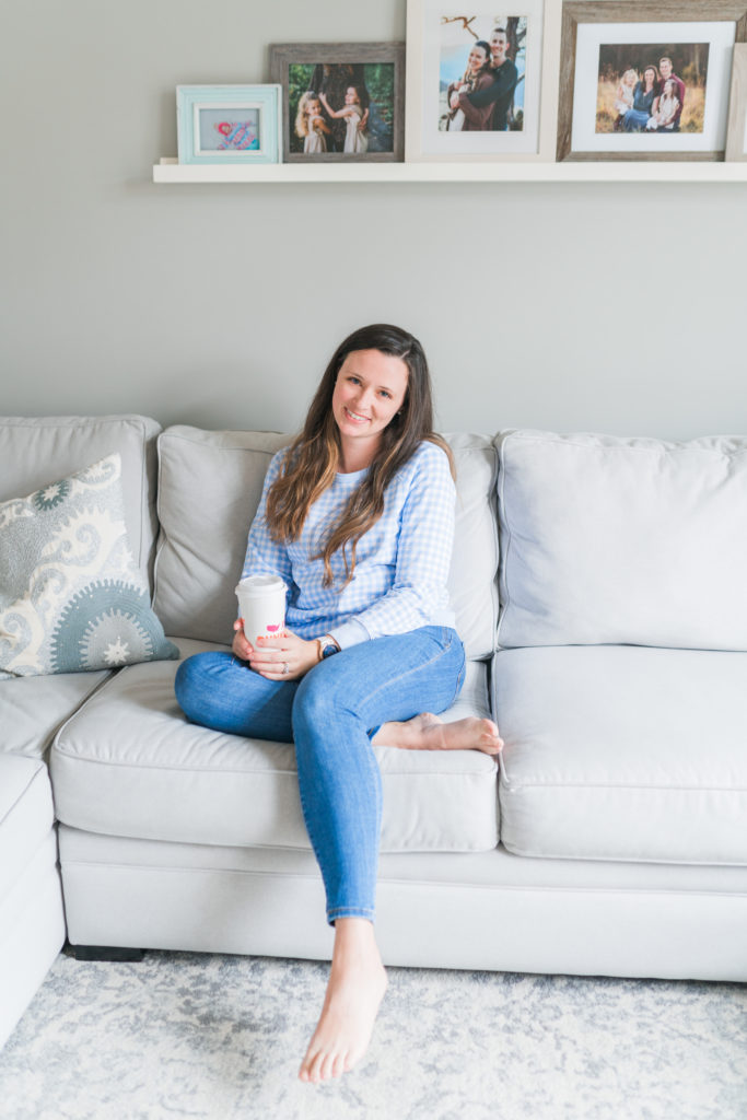 woman sitting on couch with photos above her 