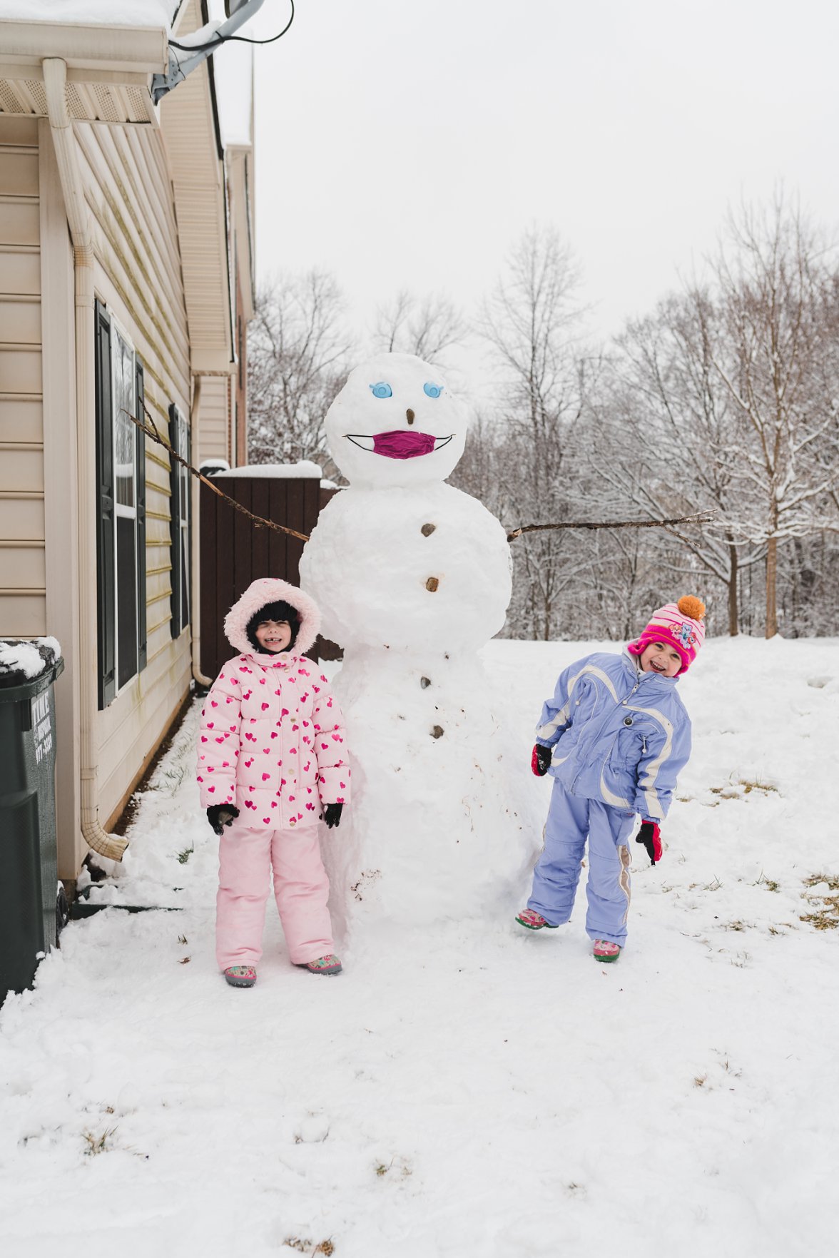 two girls next to big snowman 