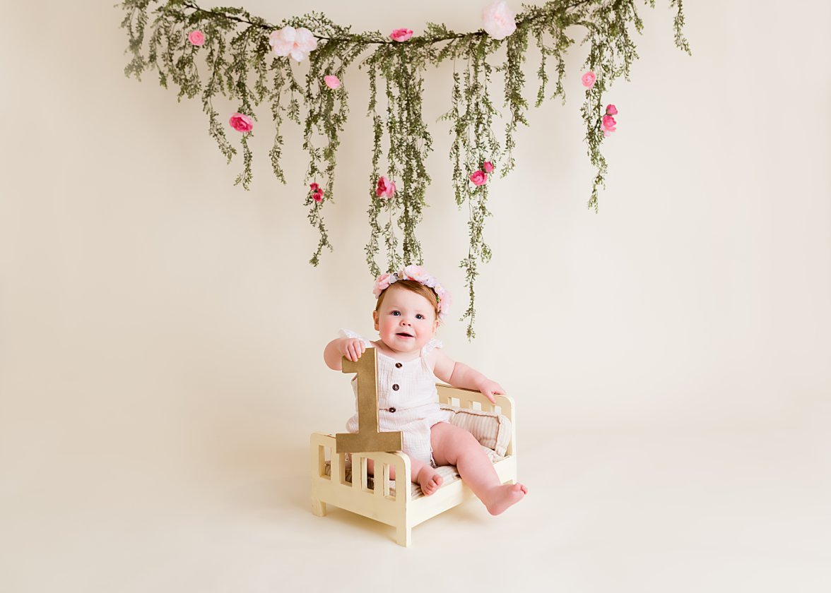baby girl sitting on tiny bed holding number one | Dayton Baby Photographer
