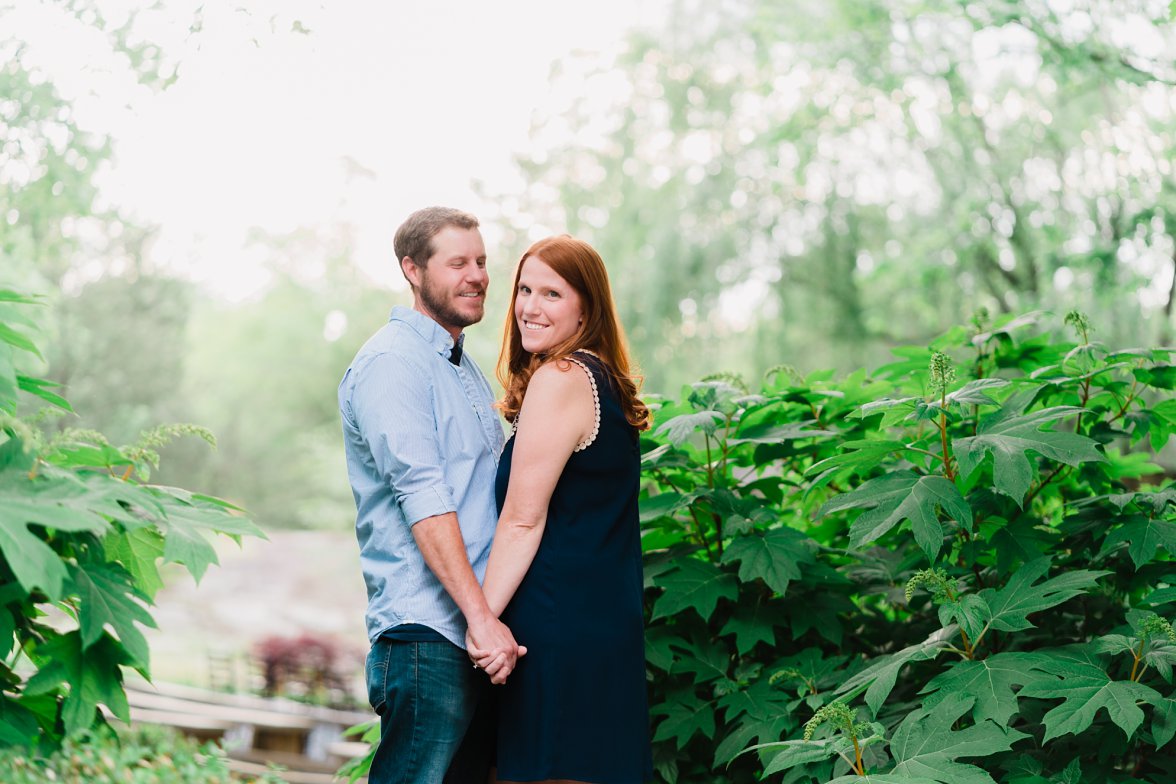 man and woman holding hands in green garden | the mill at fine creek engagement