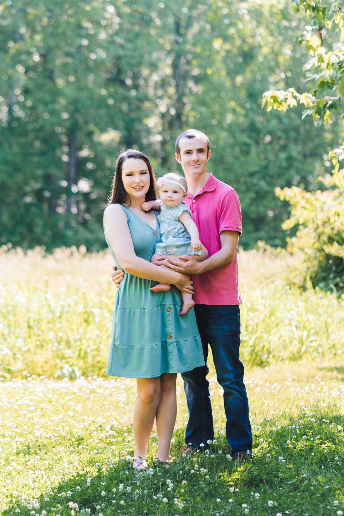 Family of three with baby girl standing in field 