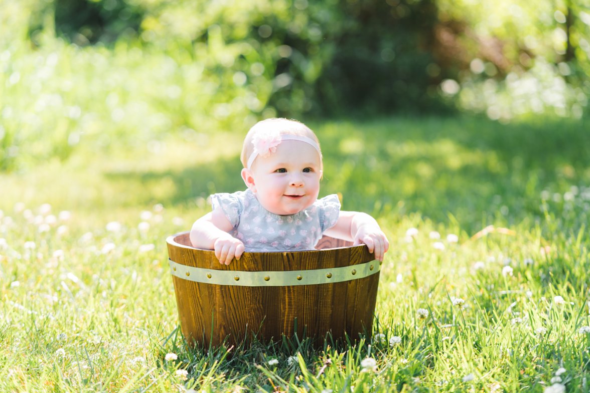 baby girl in a wood bucket smiling
