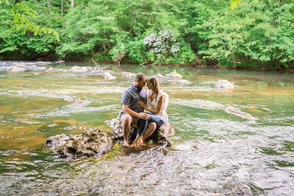 man and woman sitting on rock in river with heads together