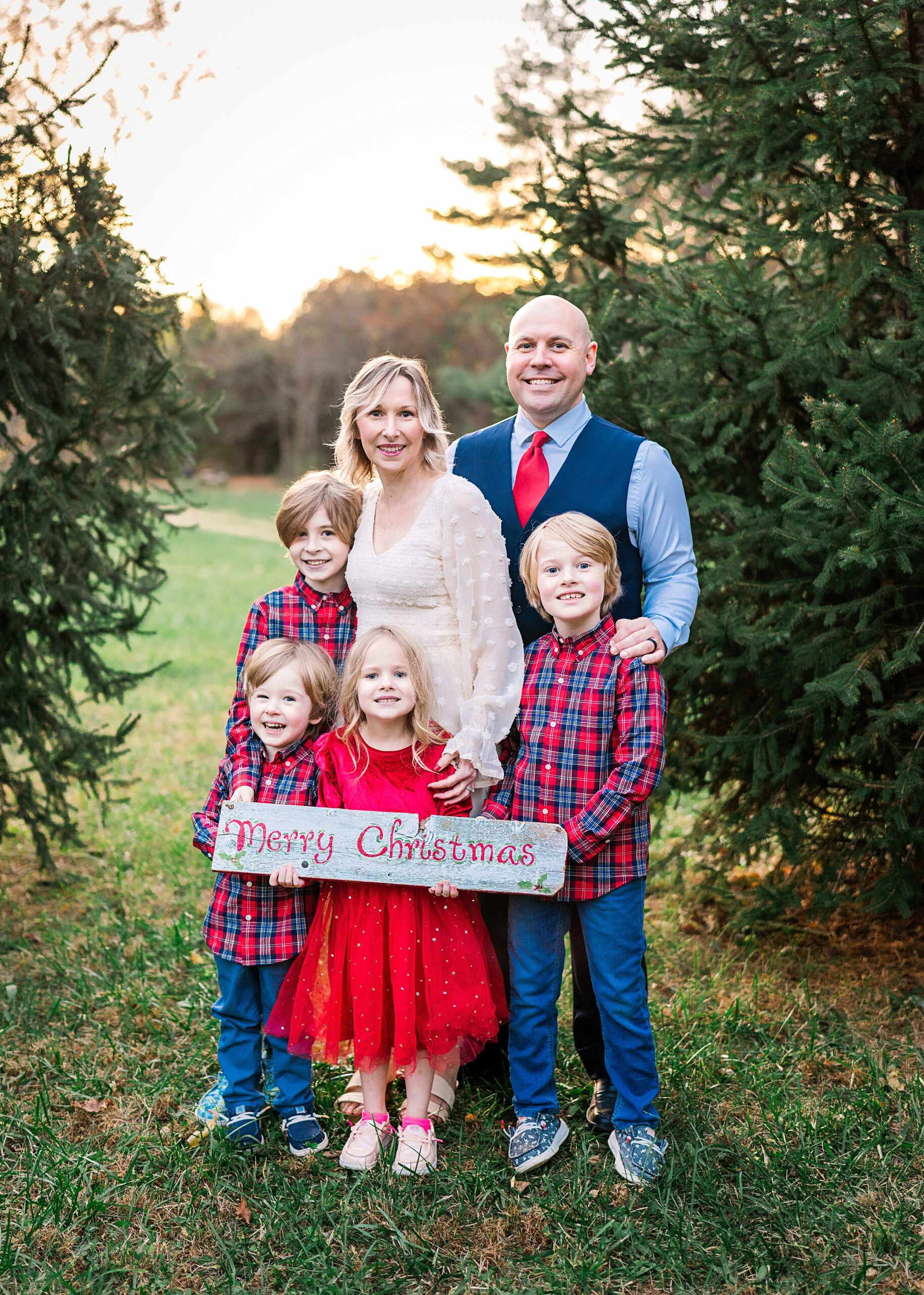 Family of five posing for holiday photo in tree farm with Christmas sign | image by Northern Virginia Family Photographer, Melissa Sheridan Photography